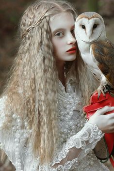 a woman with long hair holding an owl