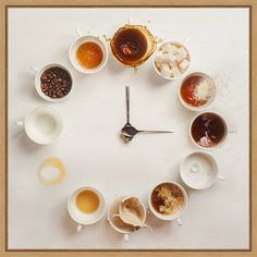 a clock made out of coffee cups and saucers on a white surface with spoons in the middle