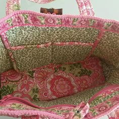 a pink and green floral purse sitting on top of a white table next to a mirror