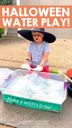 a little boy in a witches hat playing with water and ice cubes on the ground