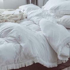 an unmade bed with white sheets and pillows