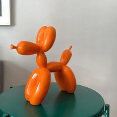 an orange balloon dog sitting on top of a green table next to a gray couch