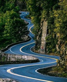 a winding road in the mountains with trees on both sides