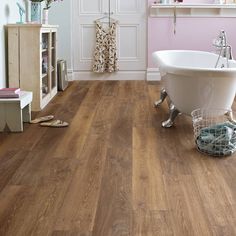 a bathroom with pink walls and wood flooring on the floors, including a claw foot bathtub