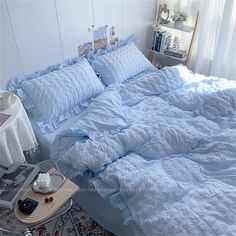 an unmade bed with blue sheets and pillows