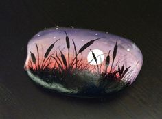 a painted rock sitting on top of a wooden table next to a black surface with grass