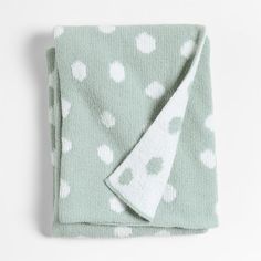 a green blanket with white polka dots on it and a white towel folded over the edge