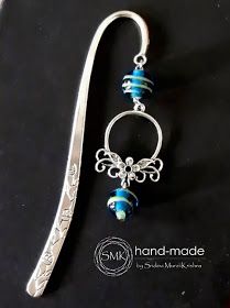 a pair of silver spoons with blue beaded beads hanging from it's side