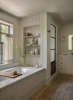 a bathroom with a bathtub, sink and shelves on the wall next to it