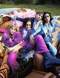 four women sitting on top of a couch covered in furs and feather boas