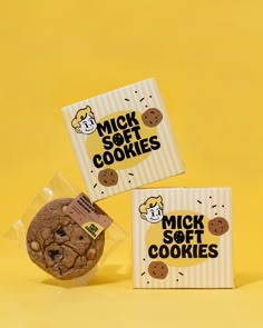 two boxes with cookies in them sitting on a yellow surface next to one box that says, mick soft cookies