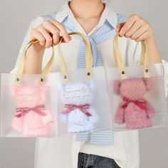 a woman holding three small bags with teddy bears in them, one is pink and the other is blue