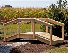 a small wooden bridge sitting in the middle of a field