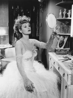 a woman in a feathered dress is looking into a mirror