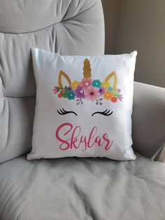 a white pillow with a unicorn's face and flowers on it that says skyr