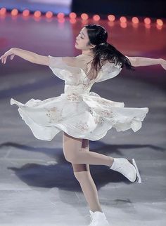 a female figure skating in a white dress