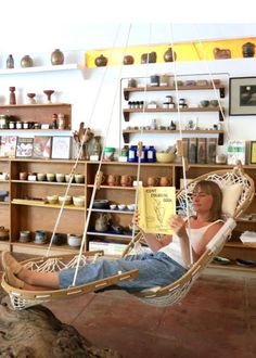 a woman sitting in a hammock reading a book