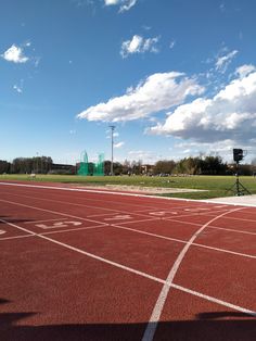 an empty running track under a cloudy blue sky