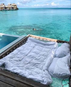 a bed sitting on top of a wooden platform next to the ocean