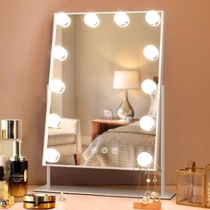 a lighted mirror sitting on top of a dresser next to a lamp and other items