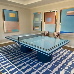 a ping pong table in the middle of a room with paintings on the walls