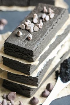 three pieces of chocolate cake with white frosting and chocolate chips on top, sitting next to each other