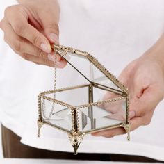 a person is holding a glass box with chains on the bottom and one hand reaching for it