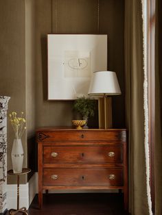 a wooden dresser sitting next to a lamp on top of a table