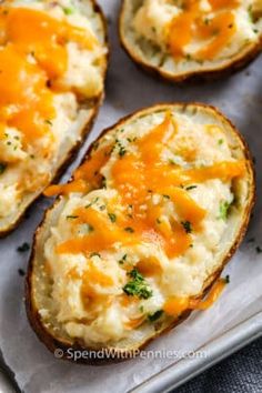 two pieces of bread with cheesy toppings on them sitting on a piece of parchment paper