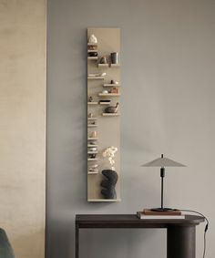 a table with a lamp and some shelves on the wall