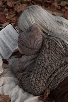 a woman laying on the ground with her head down and reading a book in front of her