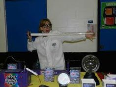 a woman in white jacket holding up a stick over her head with other items on the table