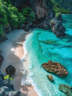 an aerial view of the beach and ocean with rocks in the foreground, surrounded by green vegetation