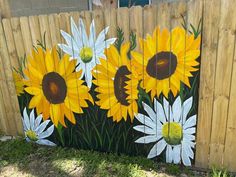 a painting of sunflowers painted on the side of a fence