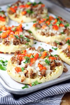 sausage and egg breakfast pizzas on a baking sheet with parsley garnish