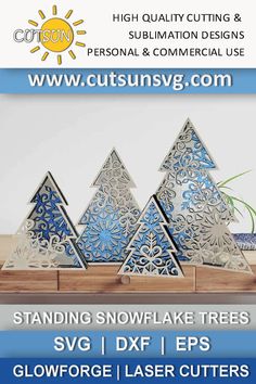 three snowflake trees are on display in front of a white wall and blue background