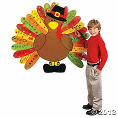 a young boy holding up a turkey shaped cutout with words written on it and wearing a top hat