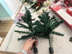 a person is making fake christmas trees out of wood and glues on the table