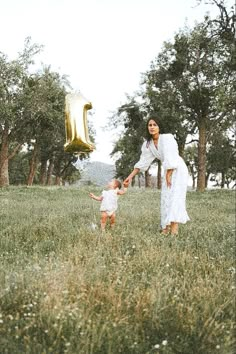 a woman and child in a field with a number one balloon