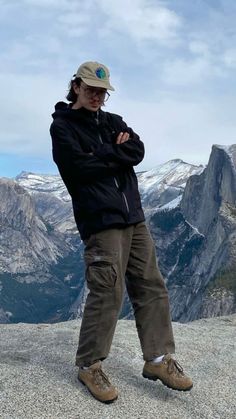 a man standing on top of a mountain with his arms crossed