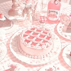 there is a cake on the table with pink flowers around it and bottles of gingham next to it