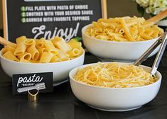 two white bowls filled with pasta next to a chalkboard sign that says, enjoy