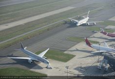 several airplanes are parked on the tarmac at an airport, including one is white and red