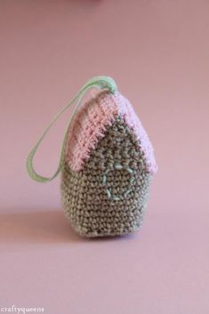 a small crocheted bag sitting on top of a pink table next to a pair of scissors