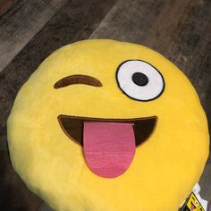 a yellow smiley face pillow with its tongue out