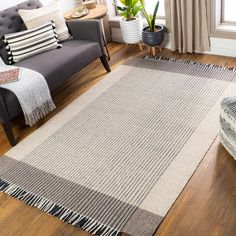 a living room filled with furniture and a rug on top of a hard wood floor