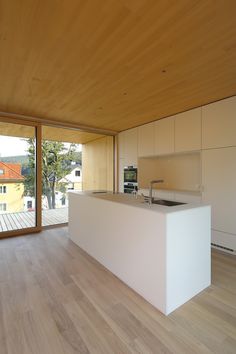 an empty kitchen with wooden floors and white counter tops on the side of the room