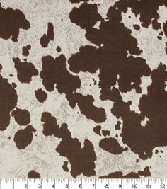 a brown and white animal print fabric with black spots on the side, in front of a ruler