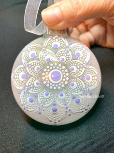 a hand holding an ornament that is decorated with blue and white designs on it