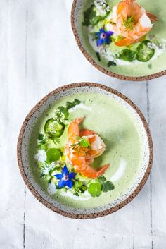 two bowls filled with food on top of a white table